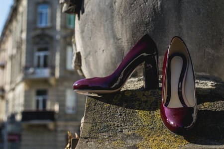 Leather cherry womens shoes on a stone wall. fashion concept, womens shoes, accessories. burgundy womens lacquered leather shoesの写真素材