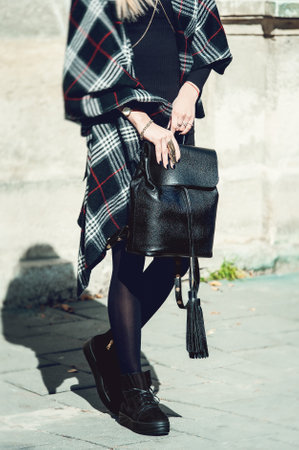 young stylish woman walking in autumn city, cold season, wearing high black boots, leather backpack, accessories, scarf, fashion trendの写真素材