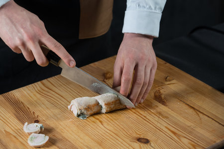 the chef cuts a meat roll on a wooden plankの写真素材
