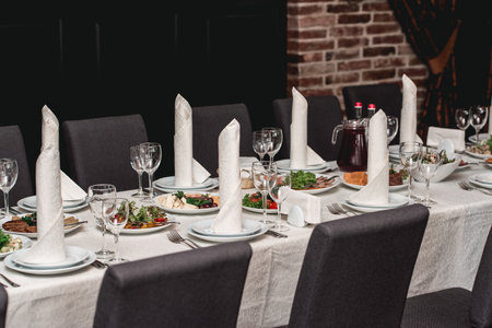 table with white tablecloth and napkins, set of cutlery with snacks for the banquet. Catering, server tables for bonquetの写真素材
