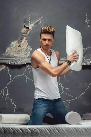 Man holding a white pillow on a gray background. Concept of comfortable sleep. orthopedic mattress and pillowの写真素材