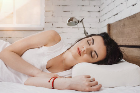 Girl sleeping on a white pillow and a mattress on a wooden bed. Concept of comfortable sleep. orthopedic mattress and pillowの写真素材