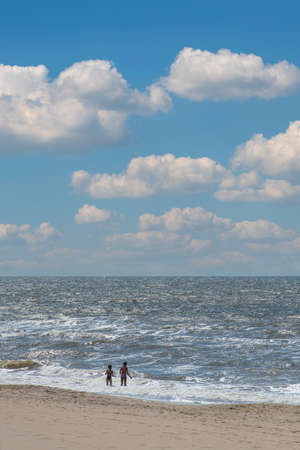 Back view of two young children running into the sea. North Sea, Zandvoort, Netherlandsの写真素材