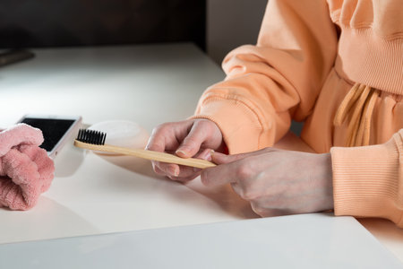 Closeup female hand is holding ecological bamboo brush with whitening toothpaste. woman is preparing...