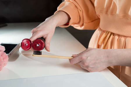 Closeup female hand is holding ecological bamboo brush with whitening toothpaste. woman is preparing going to clean teeth. Tool for oral care. Personal hygiene product conceptの写真素材