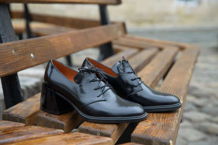 Womens leather boots close-up. black shiny oxford style shoes on a wooden benchの写真素材