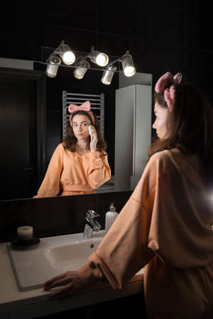Portrait view of beautiful young woman getting ready in home bathroom. mirror face reflection.の写真素材