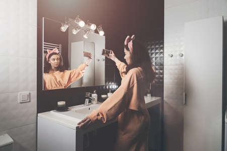 Portrait view of beautiful young woman making selfie in home bathroom. mirror face reflection....