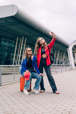 Two joyful cheerful girls taking a selfie while standing together at street near the mallの写真素材