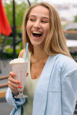 A womans hand holds a refreshing cocktail in a glass with a tube.の写真素材