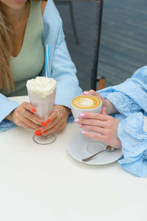 Two girls having a cup of coffee outdoorsの写真素材