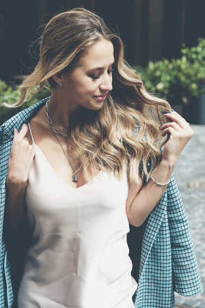 Fashionable young woman with blond hair dressed in beige dress and checkered coat posing.の写真素材