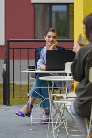 Charming happy woman student using laptop computer to prepare for the course work.の写真素材