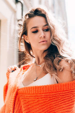 Portrait of fashionable women in orange sweater and beige dress posing in the street. tonedの写真素材
