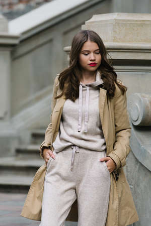 Portrait of fashionable women in beige sports suit and trench coat posing on the streetの写真素材
