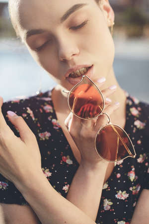 Portrait of a stylish young woman. Brunette with ballerina hairstyle in sundress posing on street. Selective focusの写真素材