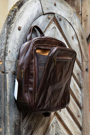 Brown leather backpack on the wooden doorの写真素材