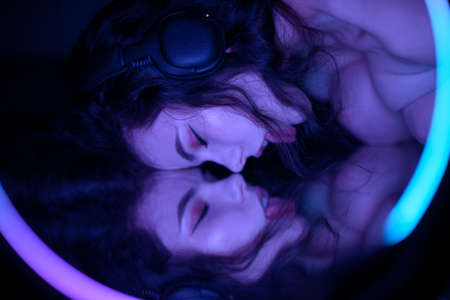 Emotional studio portrait of a young woman in a wireless headphones with ring flash effect. Round LED Circle Lamp.の写真素材
