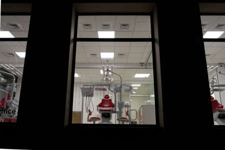 new dental office. night dentistry. red dental chair, view through the windowの写真素材