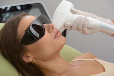 Cosmetology. Closeup of beautician hands doing beauty treatment for female face at spa salon. Facial...