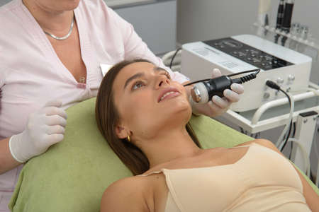 Non injection mesotherapy. Doctor and patient in clinic. Rejuvenation cosmetology tool. Woman...