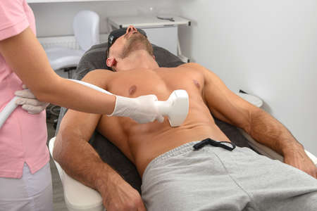 Laser hair removal on mans belly. Doctor and patient in clinic.の写真素材
