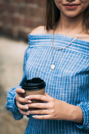 A female in a striped jumpsuit posing with a coffe cupの写真素材