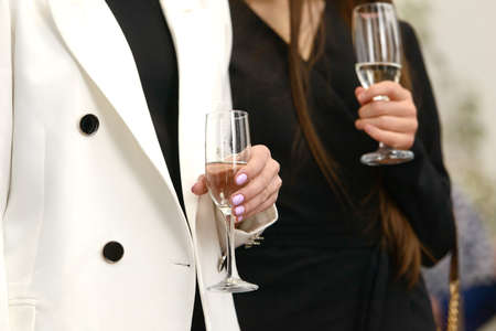 Luxurious woman wearing a white jacket, holding a glass with champagneの写真素材
