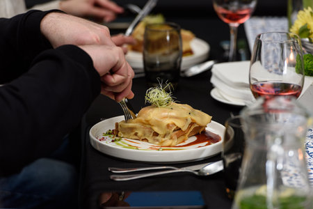 Man eating Francesinha, traditional Portuguese sandwich in a restaurant. National cuisine conceptの写真素材