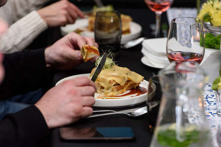 Man eating Francesinha, traditional Portuguese sandwich in a restaurant. National cuisine conceptの写真素材