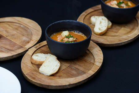 Seafood spicy soup with potatoes, shrimps, herbs and fish from a picad closeup in a pan served with...