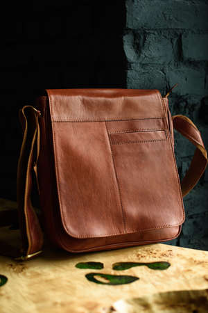 close-up photo of orange leather messanger bag on a wooden tableの写真素材