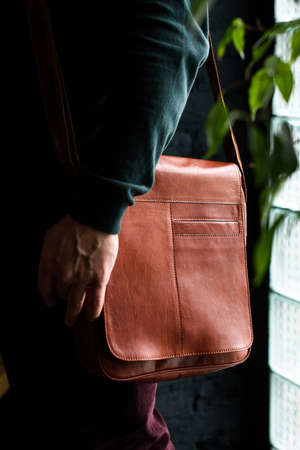 close-up photo of orange leather bag on mans shoulderの写真素材