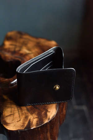 hand made black leather wallet on a wood . Leather craft. Selective focus