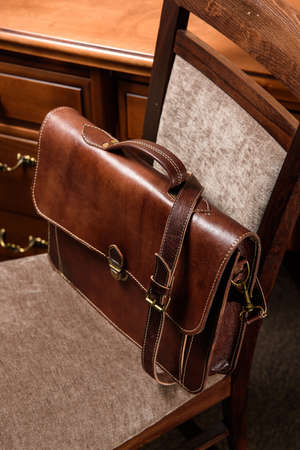 brown leather briefcase with antique and retro look for man on a chair. Hotel room photoの写真素材