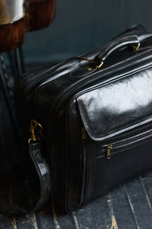 Leather black travel bag, on a black wooden floorの写真素材