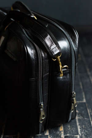 Leather black travel bag, on a black wooden floorの写真素材