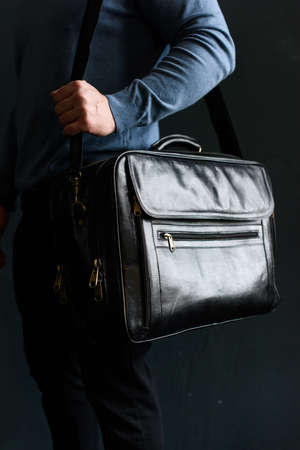 Man holding black leather travel bag. Soft light