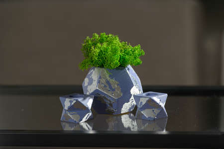 green moss in a violet concrete pot with two candle holdersの写真素材