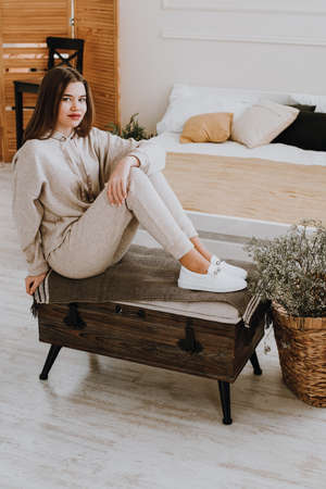 photo of a women in beige sports suit and stylish white leather sneakers posing on a bench. selective focusの写真素材