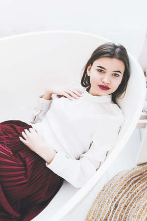 Portrait of fashionable women in red skirt and white blouse posing in a bathの写真素材