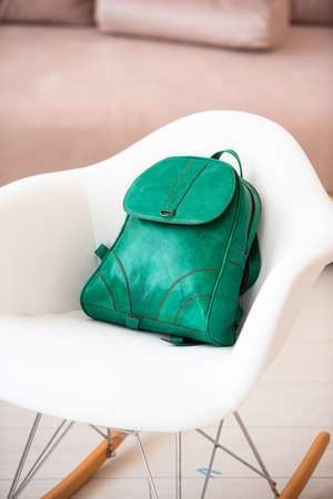 A green leather modern backpack on a white chairの写真素材