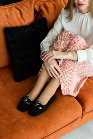 Photo of a womens legs in suede high-heeled shoes with a buckle. Posing on a sofaの写真素材