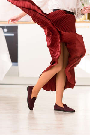 Photo of womens legs in a stylish suede burgundy loafers. Woman wearing red skirt.の写真素材
