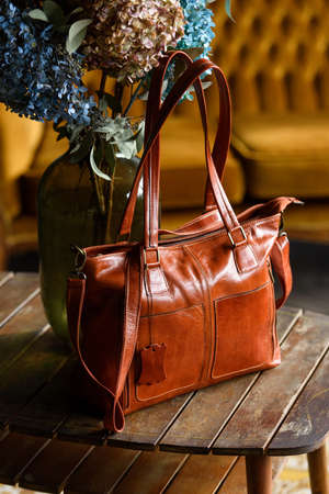 close-up photo of orange leather bag on a wooden tableの写真素材