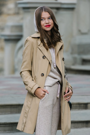 Portrait of fashionable women in beige sports suit and trench coat posing on the streetの写真素材