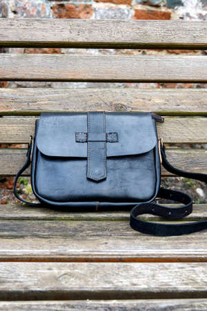 close-up photo of black leather handbag on a wooden benchの写真素材