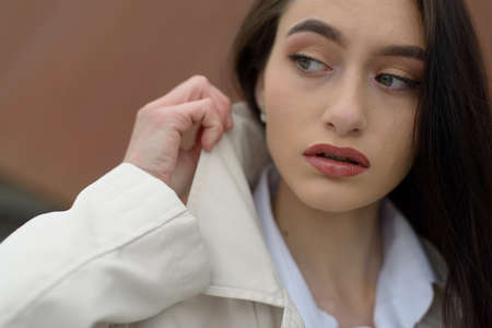 Outdoor portrait of a young beautiful fashionable lady wearing stylish coat . Model looking aside. Female fashion concept. City lifestyle. Close up.の写真素材
