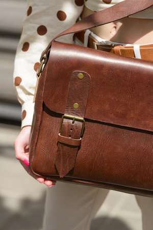 Part photo of a woman with a brown leather briefcase with antique and retro look. Outdoors photoの写真素材