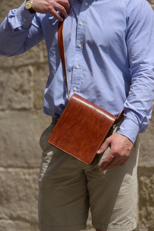 close-up photo of a small orange leather bag in mans handの写真素材